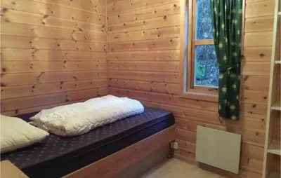 a bed in a log cabin with a window at 3 Bedroom Nice Home In Vallavik in Vangsbygd
