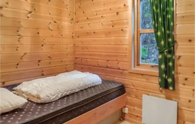 a log cabin with a bed in a room with a window at 3 Bedroom Pet Friendly Home In Vallavik in Vangsbygd