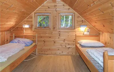two beds in a log cabin with two windows at 3 Bedroom Pet Friendly Home In Vallavik in Vangsbygd