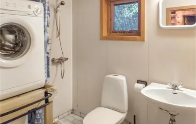 a bathroom with a toilet and a sink and a washing machine at 3 Bedroom Pet Friendly Home In Vallavik in Vangsbygd