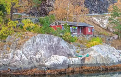 a red house on a hill next to the water at 2 Bedroom Cozy Home In Vallavik in Vangsbygd