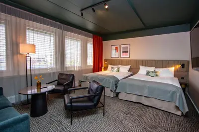 a hotel room with two beds and a table and chairs at Quality Hotel Prinsen in Trondheim