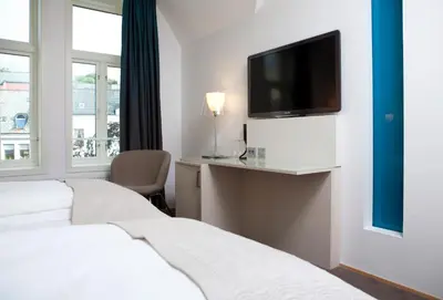 a hotel room with two beds and a flat screen tv at Quality Hotel Waterfront in Ålesund