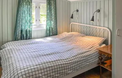 a bed in a bedroom with blue curtains and a window at Three-Bedroom Holiday Home In Sjusjoen in Sjusjøen