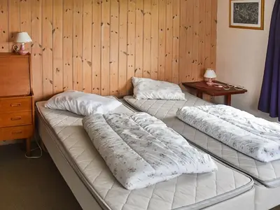 two beds in a room with a wooden wall at 8 person holiday home in FINNÅS in Vordnes