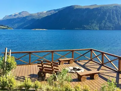 two benches sitting on a wooden deck near a lake at 5 person holiday home in EIDSVÅG in Eidsvåg