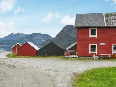 a red house and two buildings with mountains in the background at 4 person holiday home in Måndalen in Sæbø
