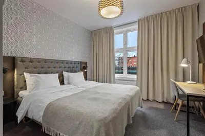 a bedroom with a bed and a desk and a window at Home Hotel Astoria in Hamar