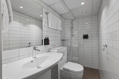 a white bathroom with a sink and a toilet at Home Hotel Astoria in Hamar