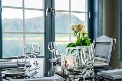 a table with wine glasses and a flower in a vase at Hustadvika Havhotell - by Classic Norway Hotels in Farstad
