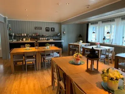 a dining room with tables and chairs and a kitchen at Nordbø Pensjonat in Hjartdal