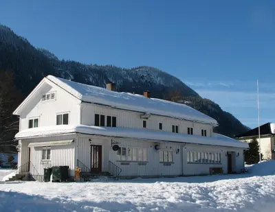 a white building in the snow with a mountain at Nordbø Pensjonat in Hjartdal