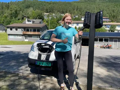 a woman is standing in front of a car at Førde Sommarhotell in Førde