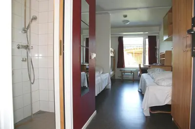 a room with two beds and a bathroom with a shower at Førde Sommarhotell in Førde