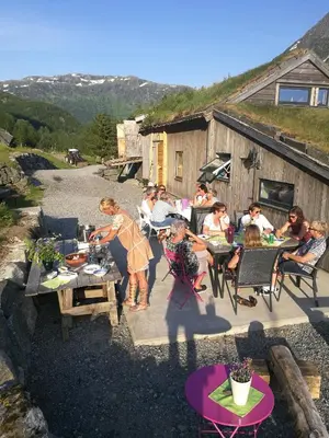 a group of people sitting at tables on a patio at Ein heilt spesiell låve i Røldal in Røldal