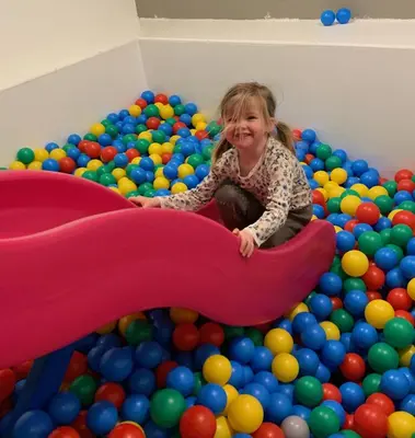 a little girl playing in a large pile of balls at Grotli Høyfjellshotell in Grotli