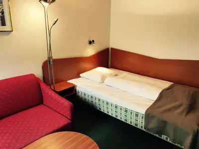 a small room with a bed and a red chair at Sødorp Gjestgivergård Motell in Vinstra
