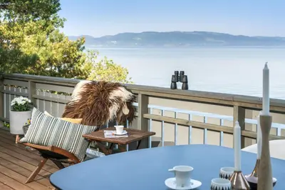 a dog sitting in a chair on a deck with a table at Private House & Bungalow by the sea in Trondheim