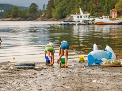 two people are playing on the beach near the water at 8 person holiday home in VÅGLAND-By Traum in Vågland