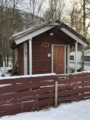 a small building with a sign on it in the snow at Skysstasjonen Cottages in Røldal