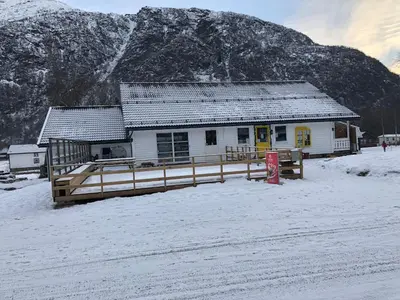 a building in the snow in front of a mountain at Skysstasjonen Cottages in Røldal
