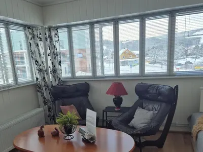 a living room with two chairs and a table and windows at Vertshuset Fannarheimr - Bed &Breakfast in Fannrem
