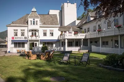 a large white house with chairs in the yard at Førde Hotel - Unike Hoteller in Førde
