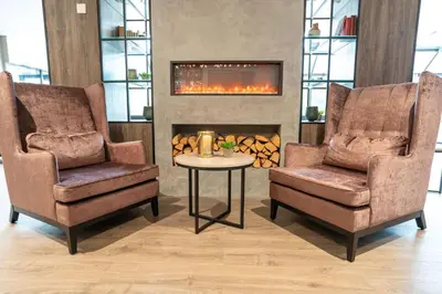 two chairs and a table in a room with a fireplace at Førde Hotel - Unike Hoteller in Førde