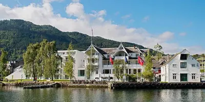 a large white building next to a body of water at Thon Hotel Sandven in Norheimsund