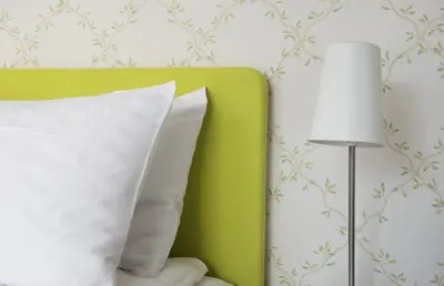 a green bed with a white pillow and a lamp at Thon Hotel Sandven in Norheimsund