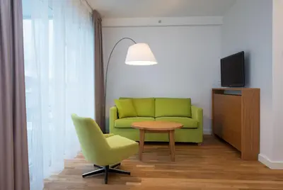 a living room with a green couch and a table at Thon Hotel Sandven in Norheimsund