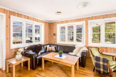 a living room with a leather couch and windows at Flåm Hostel & Cabins in Flåm