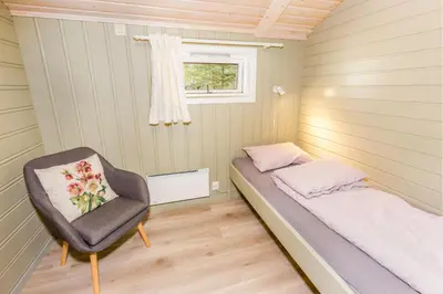 a small bedroom with a bed and a chair at Flåm Hostel & Cabins in Flåm