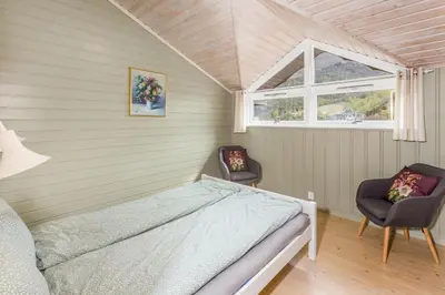 a bedroom with a bed and two chairs at Flåm Hostel & Cabins in Flåm