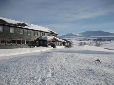 a house in the snow next to a building at Høvringen Fjellstue in Høvringen