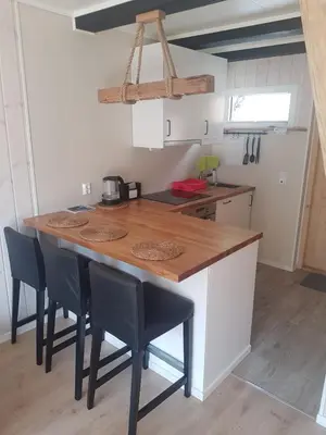a kitchen with a wooden counter top and chairs at Bazyl Apartment in Folkedal