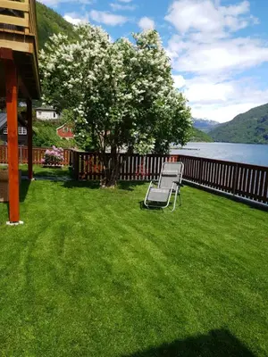 a bench sitting on a lawn next to a lake at Bazyl Apartment in Folkedal