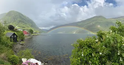 a rainbow over a lake with a red house and mountains at Bazyl Apartment in Folkedal