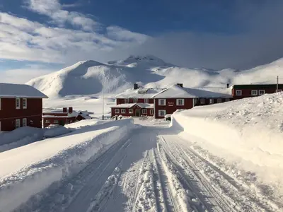 a street covered in snow with houses and mountains at Bygdin Høyfjellshotell in Beitostøl