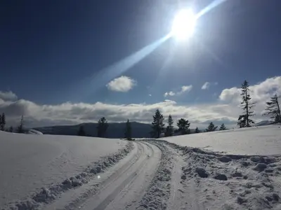 a snow covered road with the sun in the sky at Tuddal Høyfjellshotel in Tuddal