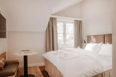 a bedroom with a bed and a table and a window at Jegtvolden Fjordhotell in Straumen