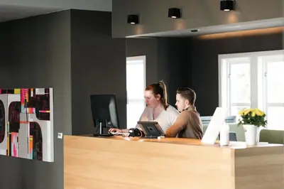 a man and woman sitting at a desk with a laptop at Jegtvolden Fjordhotell in Straumen