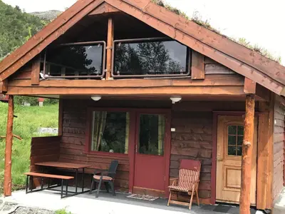 a cabin with a red door and a table and chairs at Bua in Viksdalen