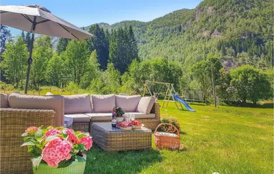 a couch sitting in the grass with a swing at 3 Bedroom Lovely Home In Vikanes in Eiknes