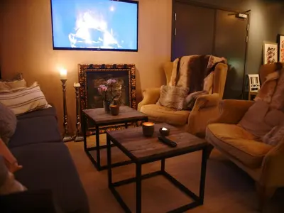 a living room with two tables and a flat screen tv at Fosen Fjord Hotel in Å i Åfjord