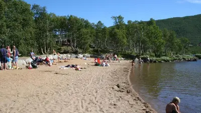 a group of people on a beach near the water at Fjelltun Fritidsleiligheter, leilighet 407 in Geilo