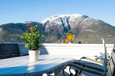 a picnic table on a balcony with a mountain at Utne Hotel in Utne