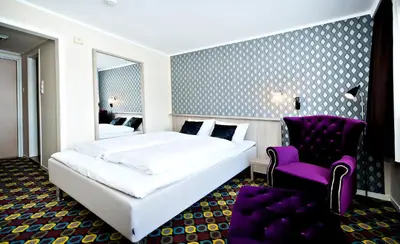 a bedroom with a white bed and a purple chair at Havila Hotel Raftevold in Hornindal