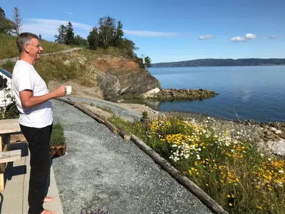 a man standing on a path next to a body of water at Hjellup Fjordbo in Leksvik