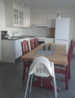 a kitchen with a wooden table and red chairs at Hjellup Fjordbo in Leksvik